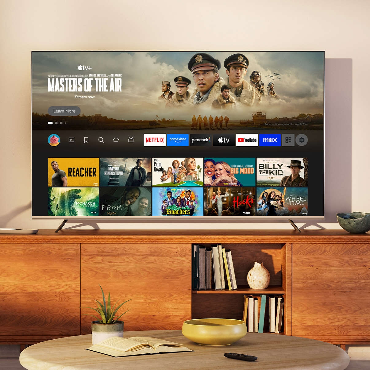 A close shot of a TV in a living room during the day. The Fire TV main menu is on screen, with Masters of the Air as the selected title. 