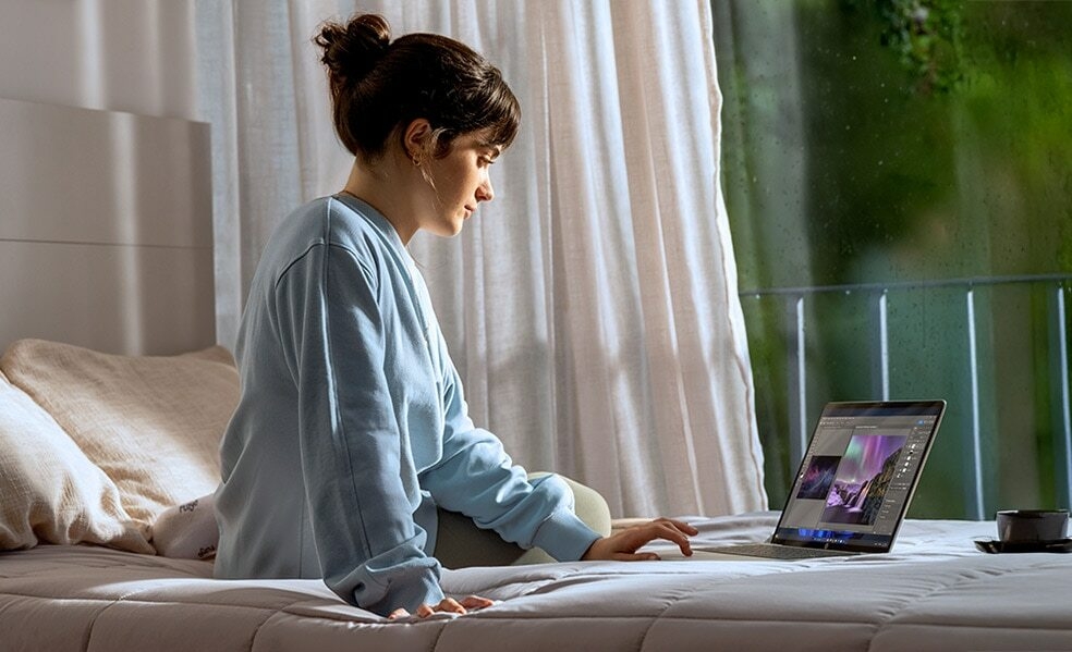 girl sitting on a bed working with a hp laptop