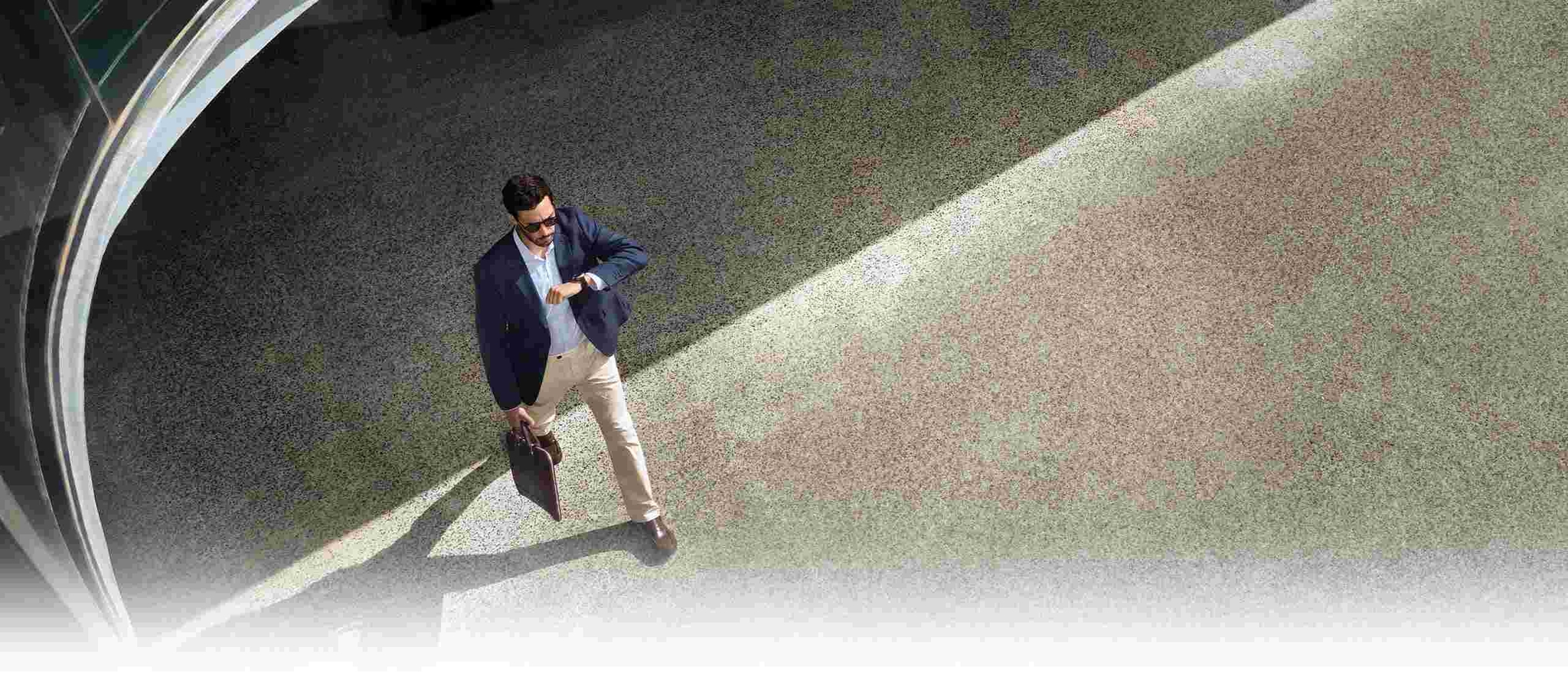 Person in a business casual outfit is looking at his Galaxy Watch8 Classic while walking.