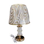 Modern white and gold table lamp, it features white fabric shade with a swirling silver/ gold partner and a gold- finished glass bodied base  